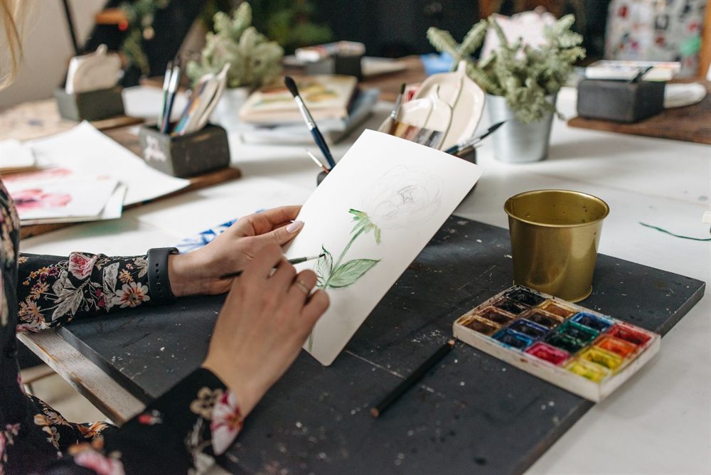 Artist painting a botanical watercolor at a workshop table