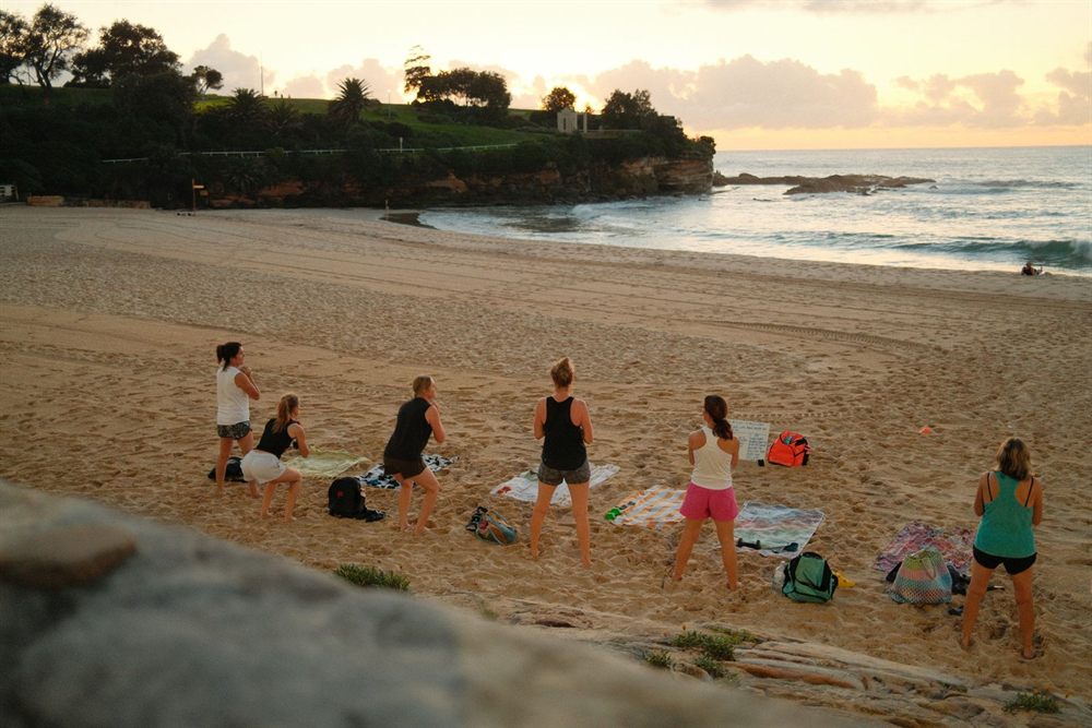 Group yoga class on a sandy beach at sunrise